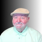 An older man with a white beard and mustache wears a light-colored flat cap and mint green collared shirt, smiling in front of a black-to-white gradient background.